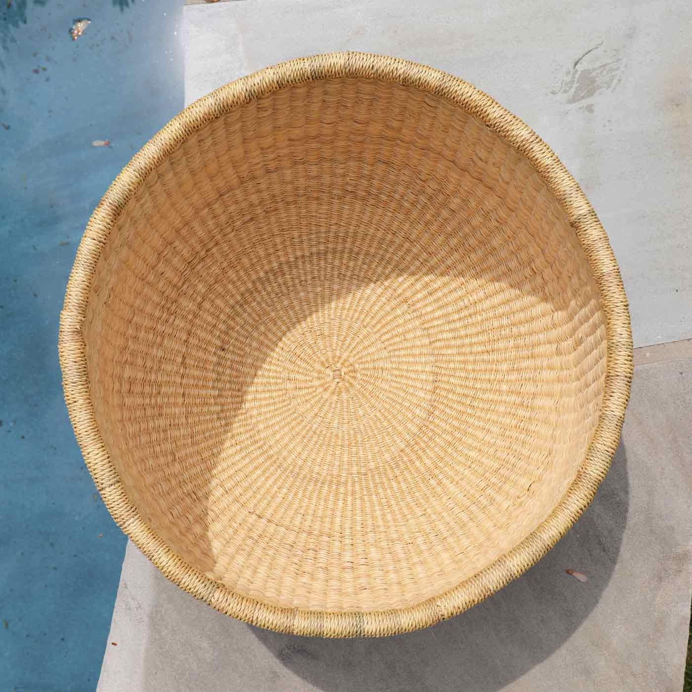 Woven basket on a concrete surface with a blue wall in the background