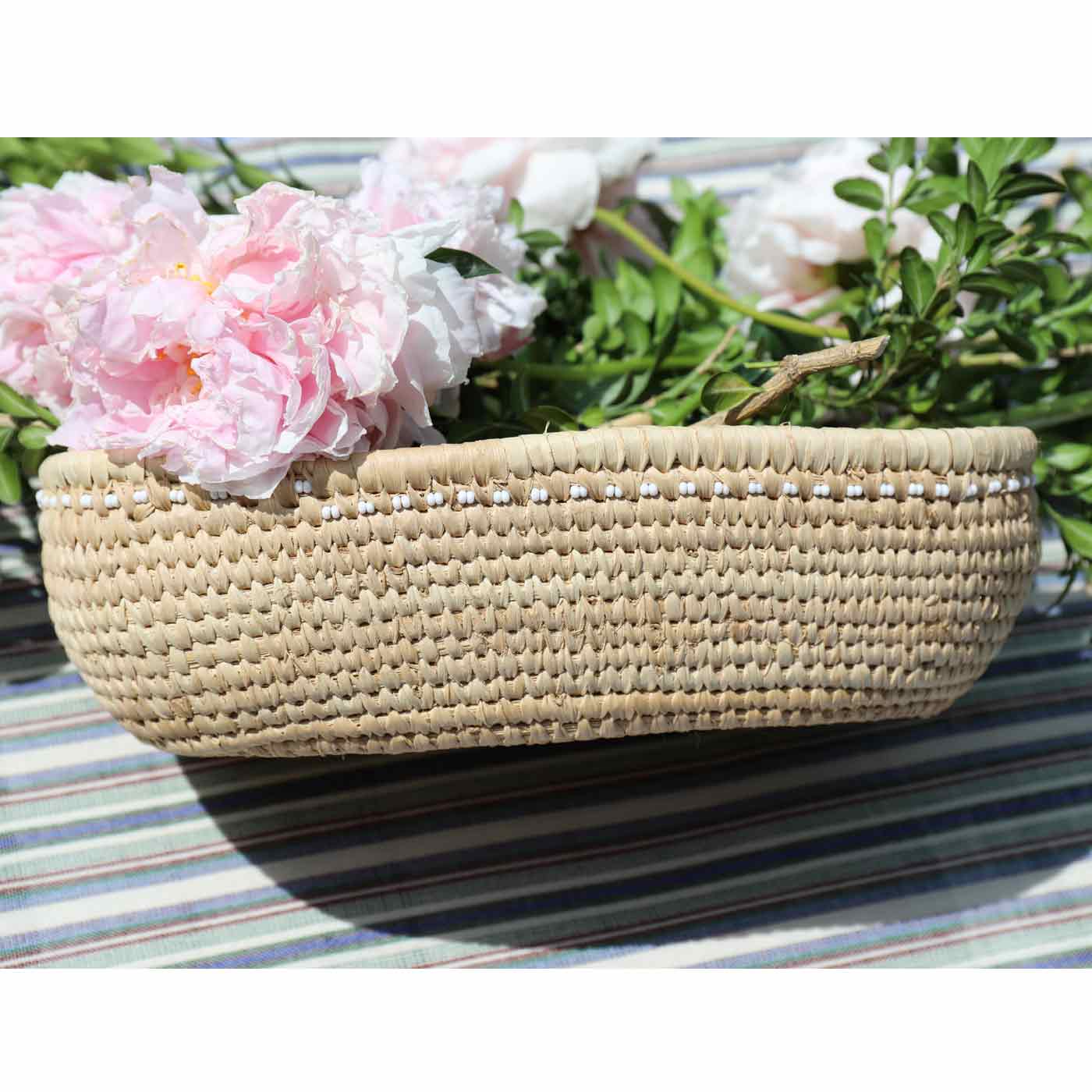 Woven basket with pink flowers on a striped surface