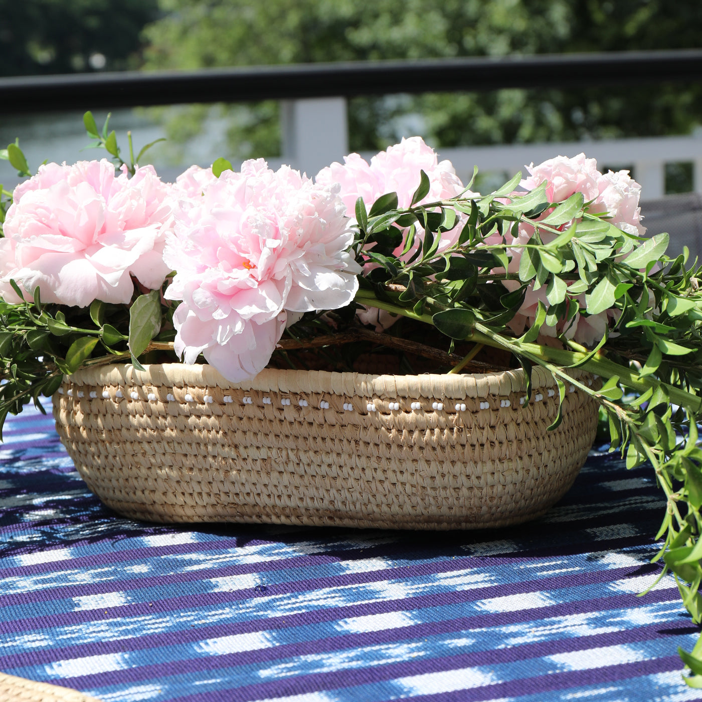Woven basket with pink flowers on a blue and white checkered tablecloth