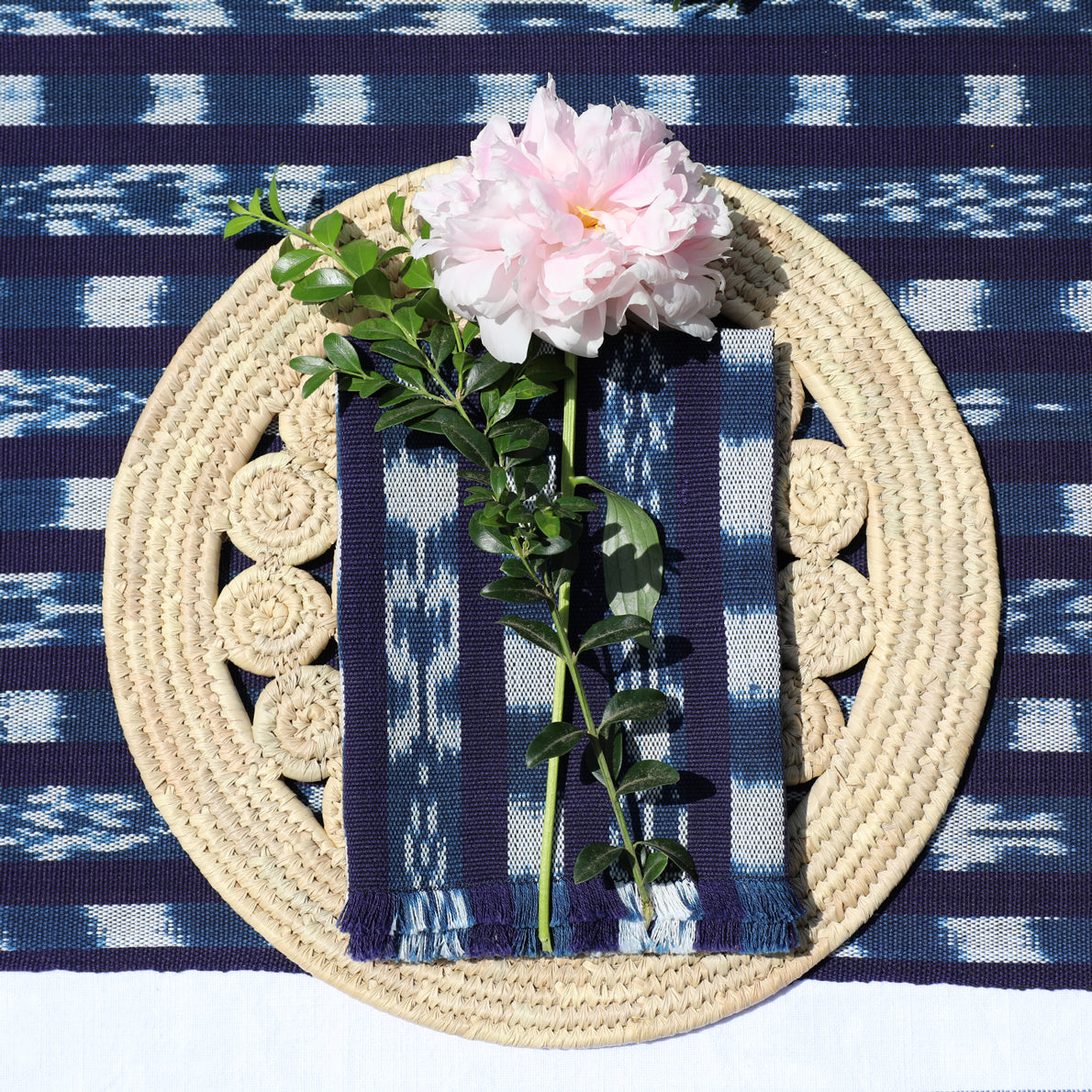 Decorative woven plate with a pink flower on a blue and white patterned fabric background