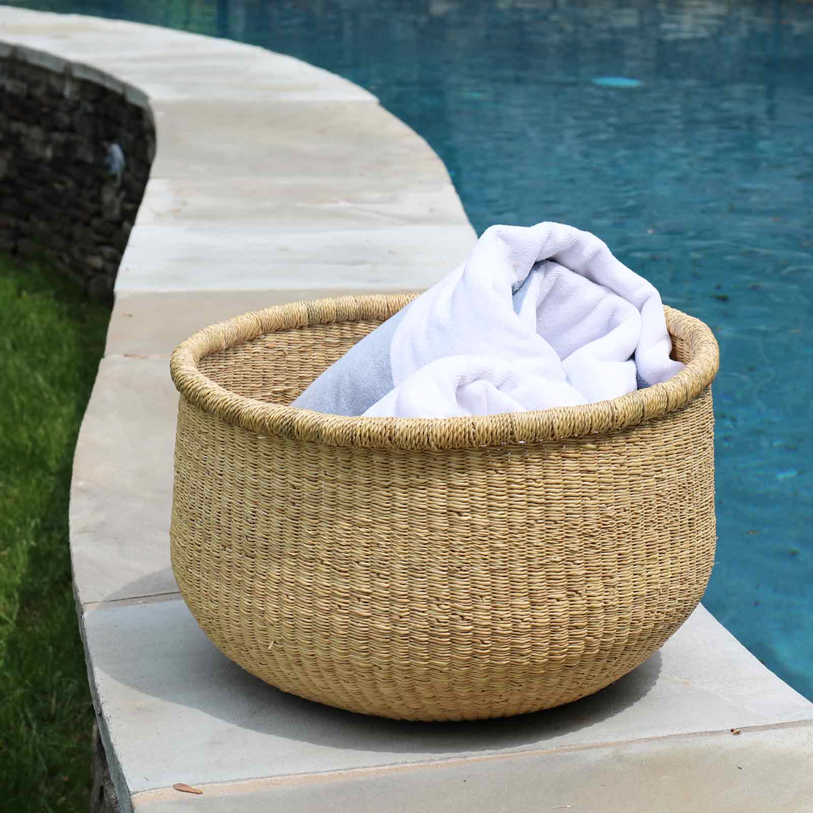 Woven basket with white towels by a poolside