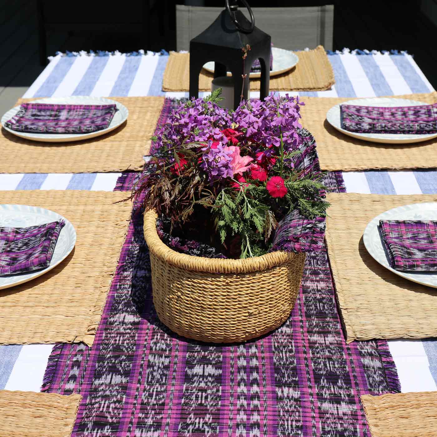 Decorative table setting with a woven basket of flowers on a striped tablecloth.