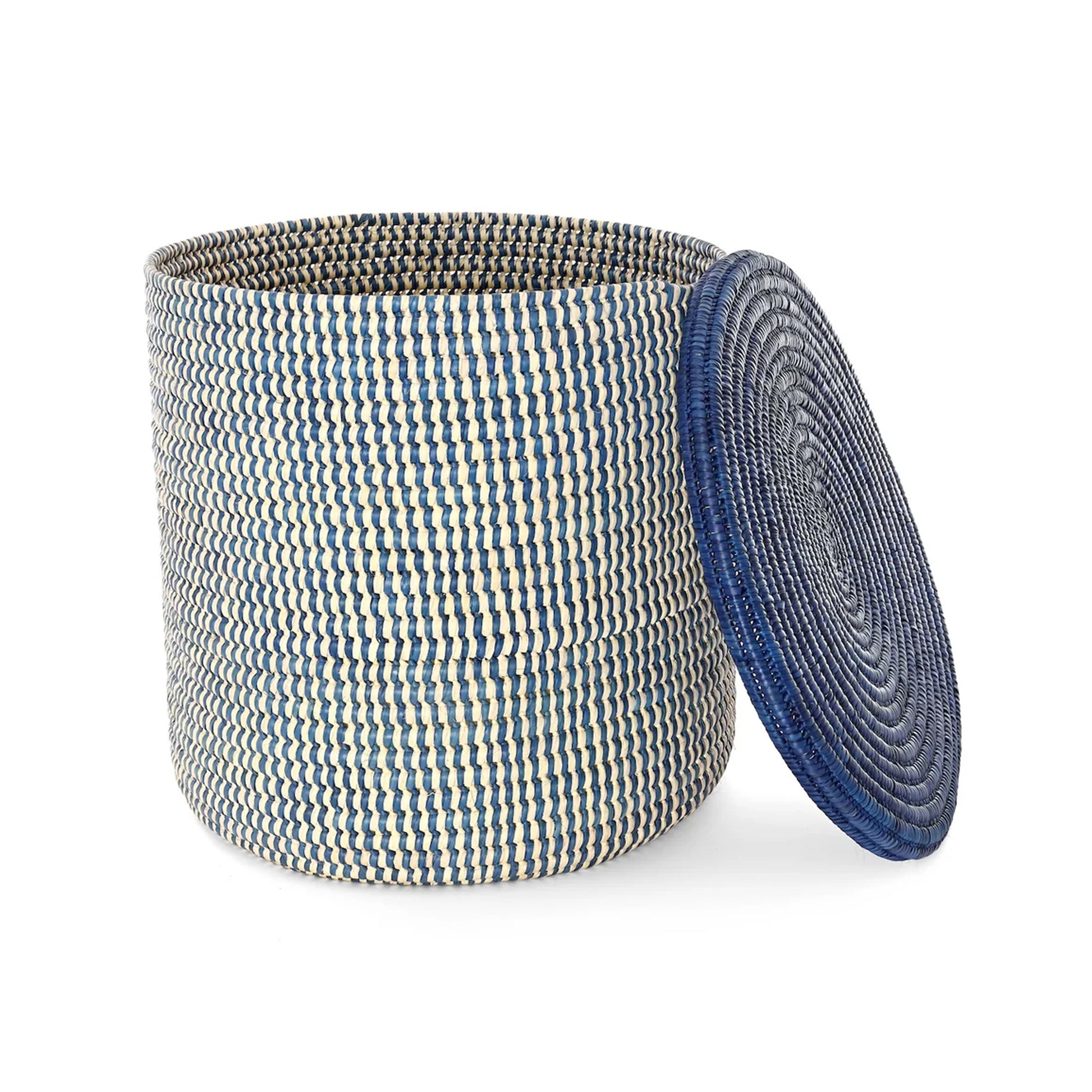 A woven storage basket with a matching round lid leaning against it on a plain white background. The basket has a textured pattern of blue, cream, and gray threads, while the lid is a solid deep blue.